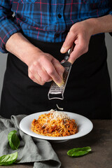 Grating cheese above bolognese pasta