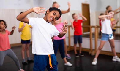 Portrait of smiling african boy showing dance elements during group class in dance center