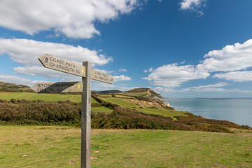 Close up of a sign post pointing toward Golden Cap mountain with Golden Cap mountain in the background © tom