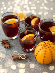 christmas and seasonal drinks concept - glasses of hot mulled wine with orange and cinnamon on grey background