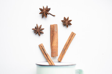star anise and cinnamon spills out of a mug on a white background. these aromatic spices are used for making mulled wine. space for text

