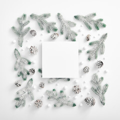 Evergreen tree branch with snow and pine cones. Square composition, flat lay, top view. Snow forest creative minimal layout with frame. White paper blank