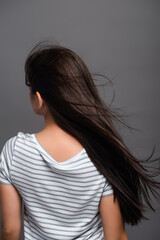 back view of wind blowing through hair of brunette woman isolated on black