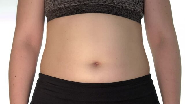 A close-up of a woman's belly with a visible navel. Young woman moves her belly. You can see skin on the abdomen moving. Belly of an obese woman.
