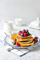Hot banana pancakes with fresh berries and honey for a breakfast.