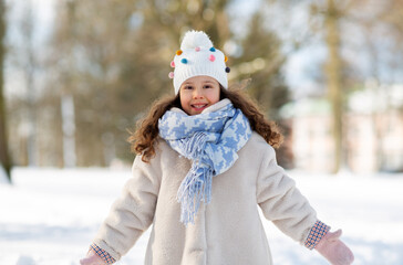 Obraz premium childhood, leisure and season concept - portrait of happy little girl in winter clothes outdoors at park
