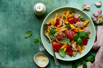 Pasta penne with tuna and vegetables in tomato sauce. Top view with copy space.