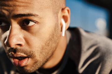 Image of african american sportsman in earphones working out