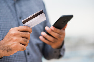 Close up businessman hand holding credit card and using smartphone to Financial administration. Buying Shopping online, Internet banking concept.