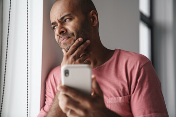 Image of brooding african american guy talking on mobile phone