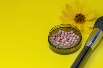 Ball blush and makeup brush close-up. Cosmetics on a bright yellow background, shallow depth of field, blur
