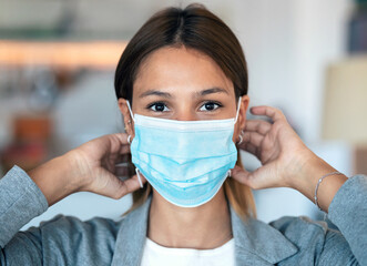 Young beautiful woman wearing an hygienic mask to prevent others from a virus while looking at camera in the home.