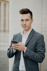 portrait of a young man, Manager, businessman in a business suit holding a phone, writing a message, thinking about work