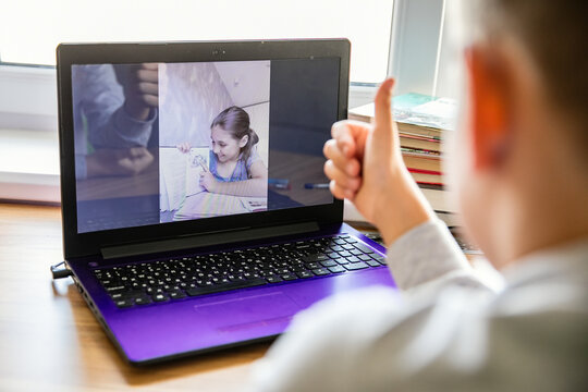 Children communicate online on a computer. The girl shows a picture in the book. The boy approves of her choice and shows a sign like it on his fingers