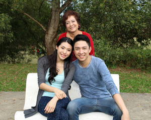 Southeast Asian family adult senior parents mother son daughter sit on park bench happy at outdoor...
