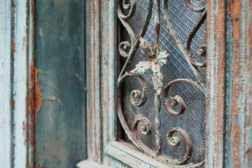 Shabby dark  painted wooden framed door with antique ornate metal gratings  Patterned lattice textures. Architectural details of vintage door of old building