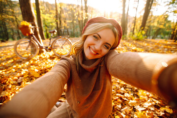 Selfie in the autumn forest. Stylish woman takes a selfie on the phone in the autumn park. Relaxation, enjoying, solitude with nature.