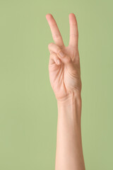 Hand showing letter V on color background. Sign language alphabet