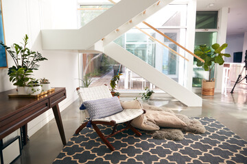 Interior View Of Beautiful Living Area With Glass Staircase And Soft Furnishings In New Family Home 