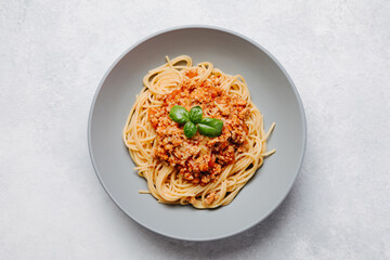 Italian spaghetti pasta with bolognese meat sauce on a light concrete, stone background