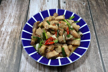 Traditional fried and stirred chopped pork belly with basil and chilly on the plate. Famous hot and spicy street food menu in Asia. 