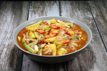 Traditional fried and stirred chopped fresh tomato, pineapple, cucumber and sliced onion in the bowl. Famous ancient red soup of vegetable in Chinese restaurant. Sweet and sour soup concept. 