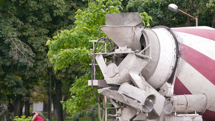Concrete mixer on a background of green trees