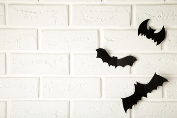 Halloween, decoration and scary concept - black paper bats flying over white background