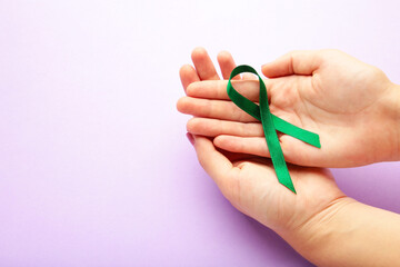 Healthcare and medicine concept - female hands holding green organ transplant awareness ribbon