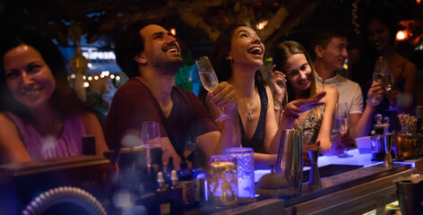 Group of young people having fun at a party at the bar, laughing and drinking alcohol