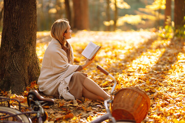 Young woman reading a book in the autumn forest. Autumn mood concept.