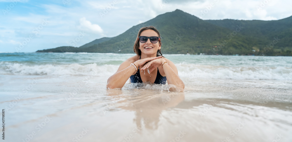 Wall mural smiling beautiful woman 40 years sunbathing on a beach in sunglasses, with a beautiful charming smil