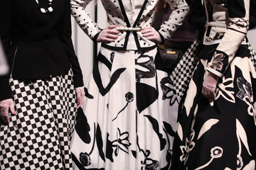Three women models in beautiful fashionable designer black and white outfits at the backstage of...