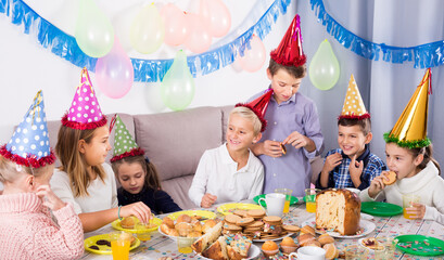 Playful children enjoying friend birthday during festive dinner.