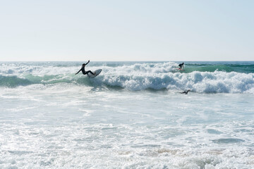 surfers off the coast of portugal catching a wave with foam