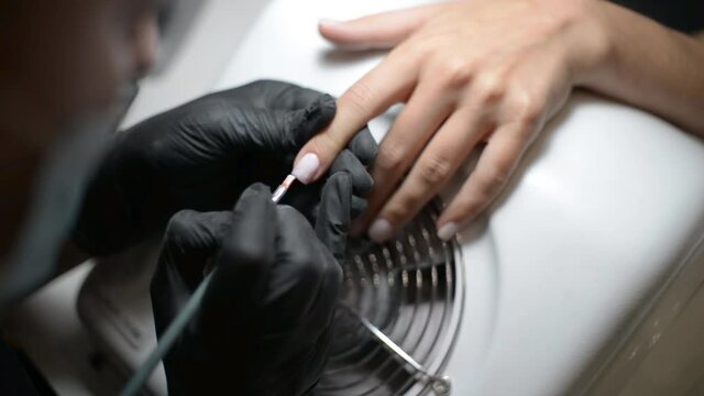 Nail Artist work in a Beauty Salon with a Hand of a Woman