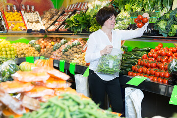 Smiling mature woman buying fresh vegetables on the market
