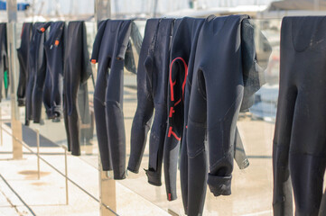 Surf suits dry in the sun on a glass fence