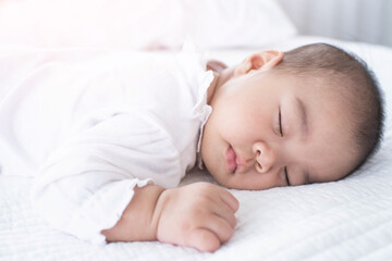 portrait of a beautiful sleeping baby on white. Cute little baby sleeping on bed at home.