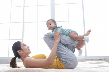Asian mother fit and play Yoga for lose weight after delivery a new born baby in home, sports mother is engaged in fitness mom, mother, exercise and healthy concept.