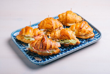A set of croissants and sandwiches with various fillings, cheese, Parma ham and salad