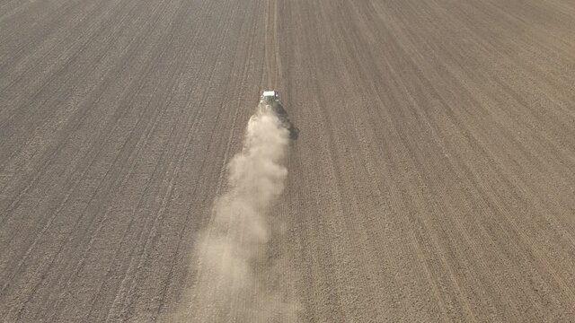 Ein Traktor f&auml;hrt &uuml;ber ein Feld und wirbelt Staub auf