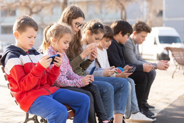 Group of children communicate using smartphones in the playground. High quality photo