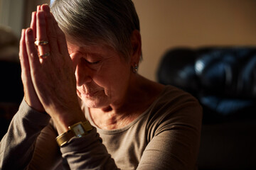 Senior woman praying at home