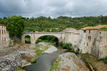 Fototapeta na wymiar The old historical architecture including the famous bridge across the small mountain river in medieval village Lagrasse, the most beautiful village of France. 