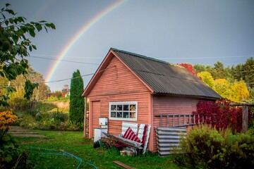 pink country house in a village in an autumn garden with a blue sky and a rainbow in the sky