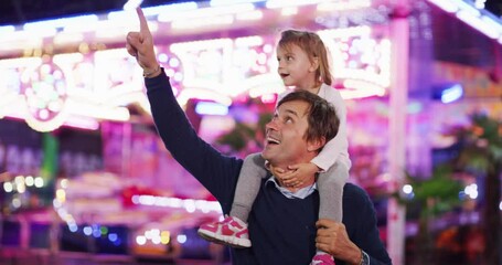 Authentic shot of a happy smiling family is having fun together in amusement park with luna park lights at night.