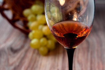 Wine glass with grapes on a wooden background.