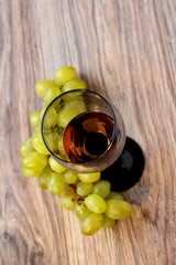 Wine glass with grapes on a wooden background.