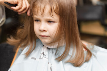 small red-haired girl 4 years old in a beauty salon. hairdressing
